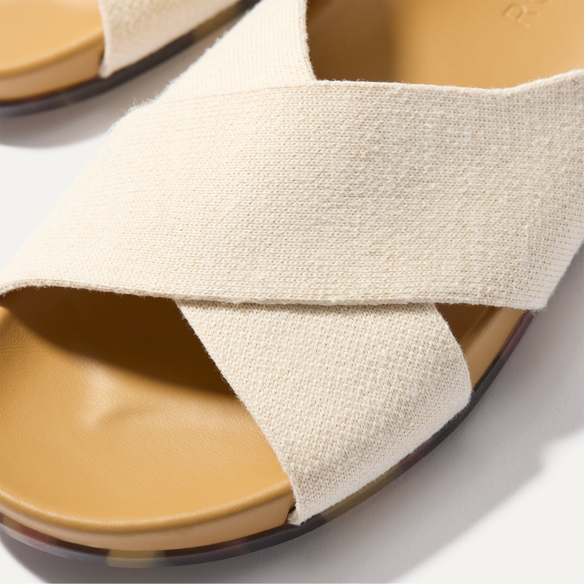 Close up of the crossing knit straps and toe of The Weekend Slide in Oat, shown in diagonal view. 