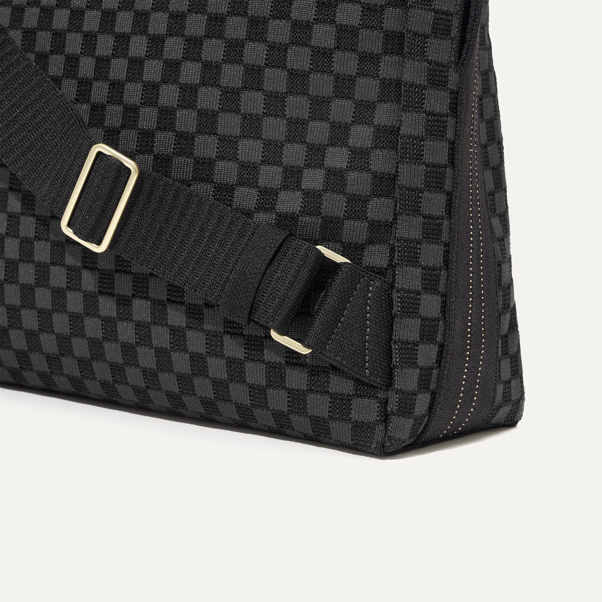 A close up of the The Backpack in Black Sand focusing on the gold hardware on the straps.