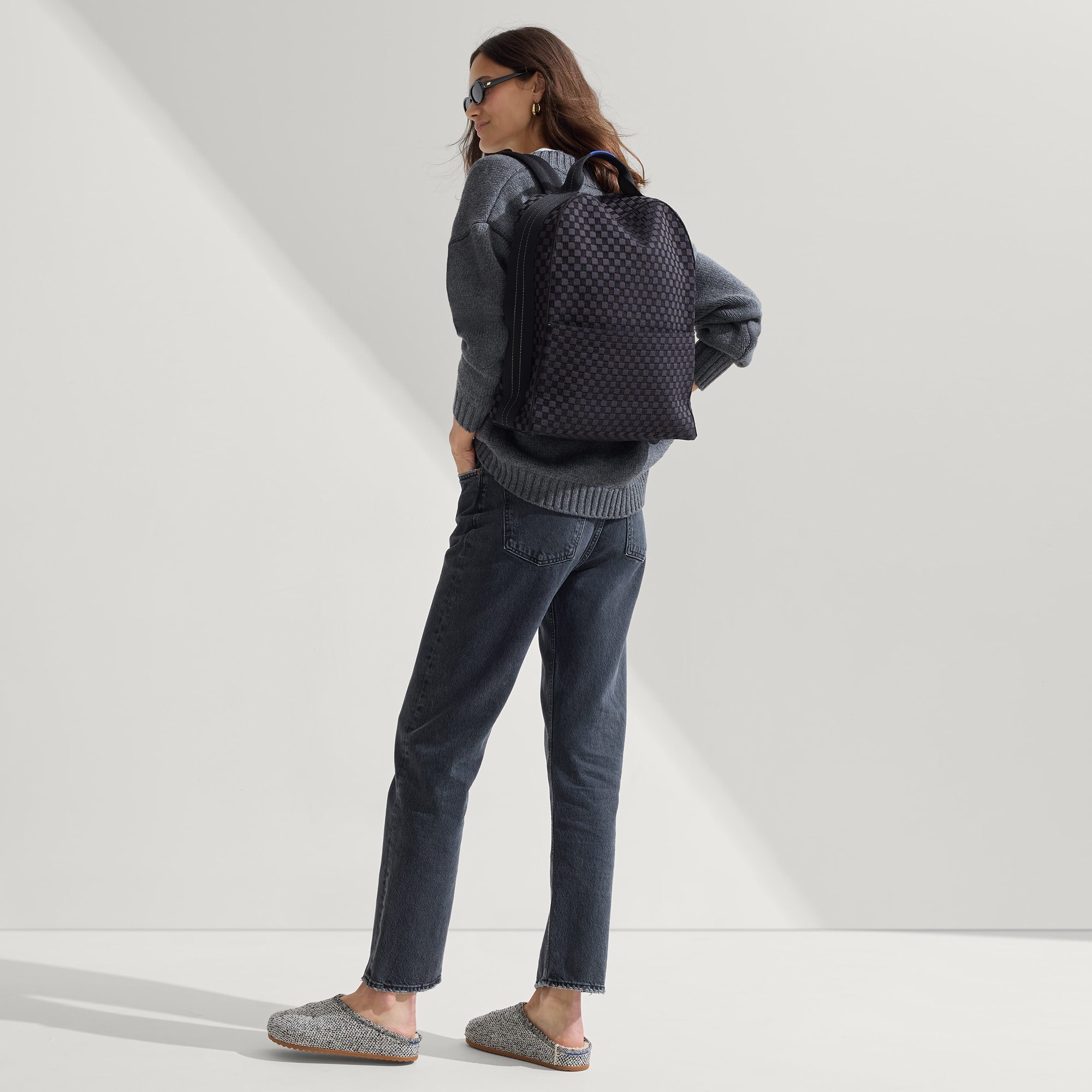 An alternate view of a model wearing The Backpack in Black Sand.
