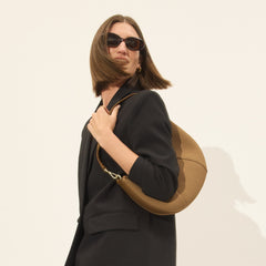 hover | Model holding The Crescent Bag in Horizon by the shoulder strap, shown from the front.