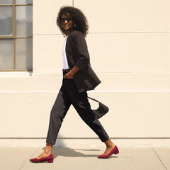An alternate view of a model holding The Mini Shoulder Bag in Black Sand.