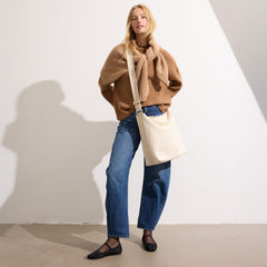 The Bucket Bag in White Sand shown worn differently on model.