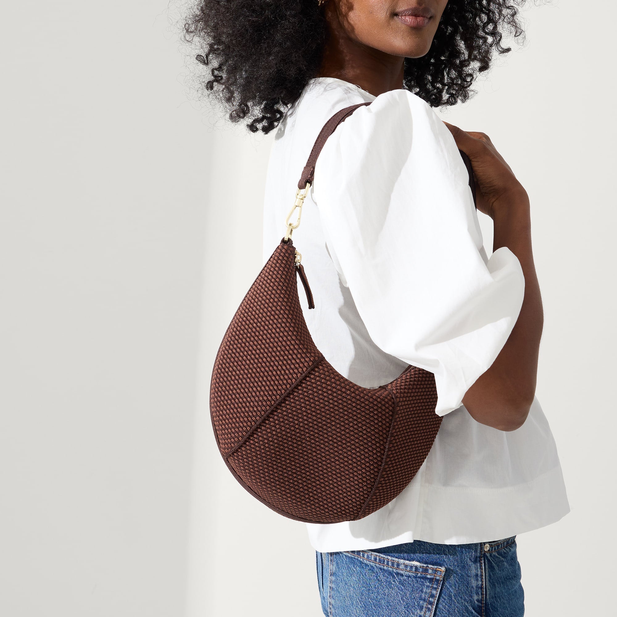 hover | Model holding The Crescent Bag in Eclipse by the shoulder strap, shown from the front.