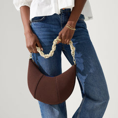 Another view of model holding The Crescent Bag in Eclipse by the shoulder strap, shown in motion.