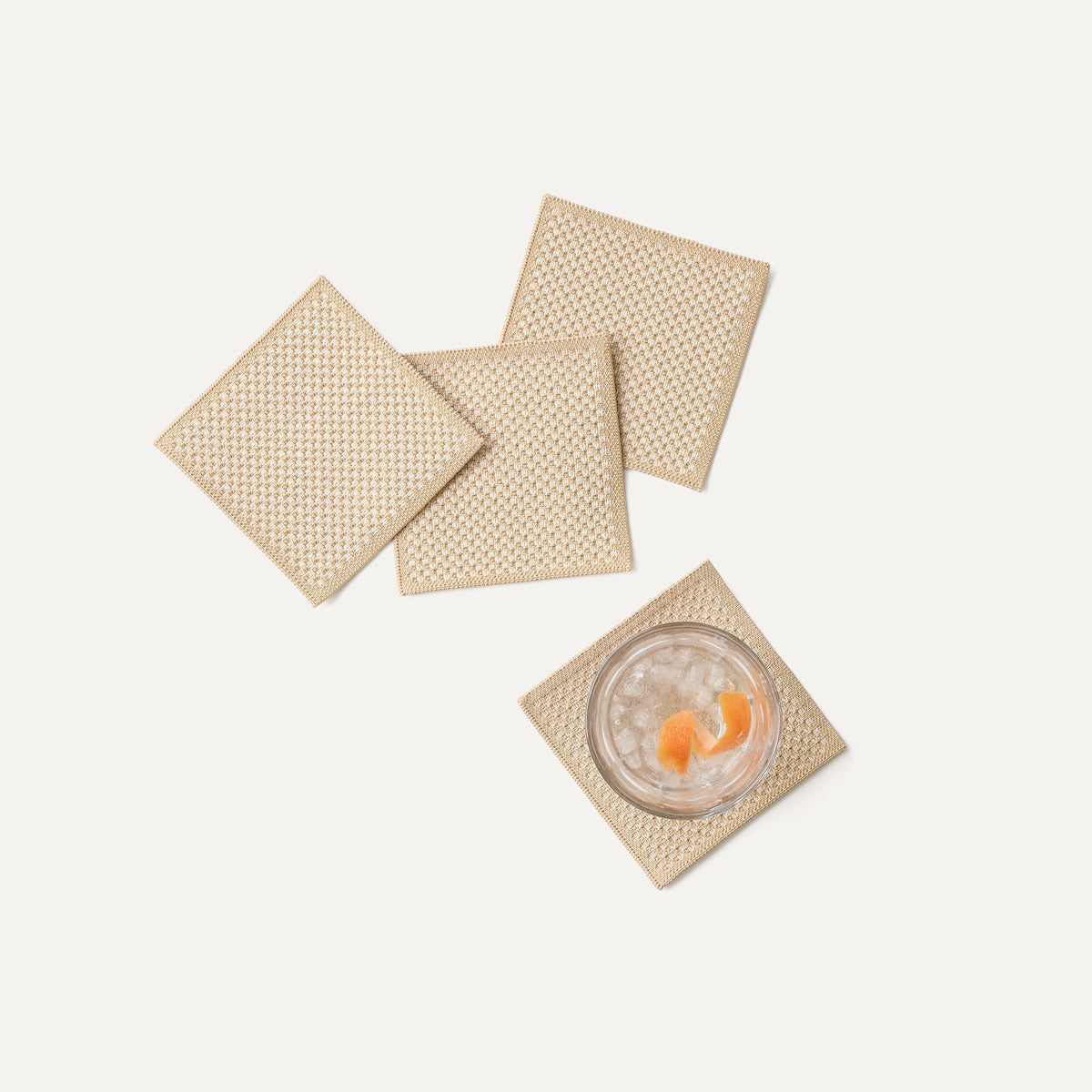 A set of four Coasters in Almond shown with a drink.