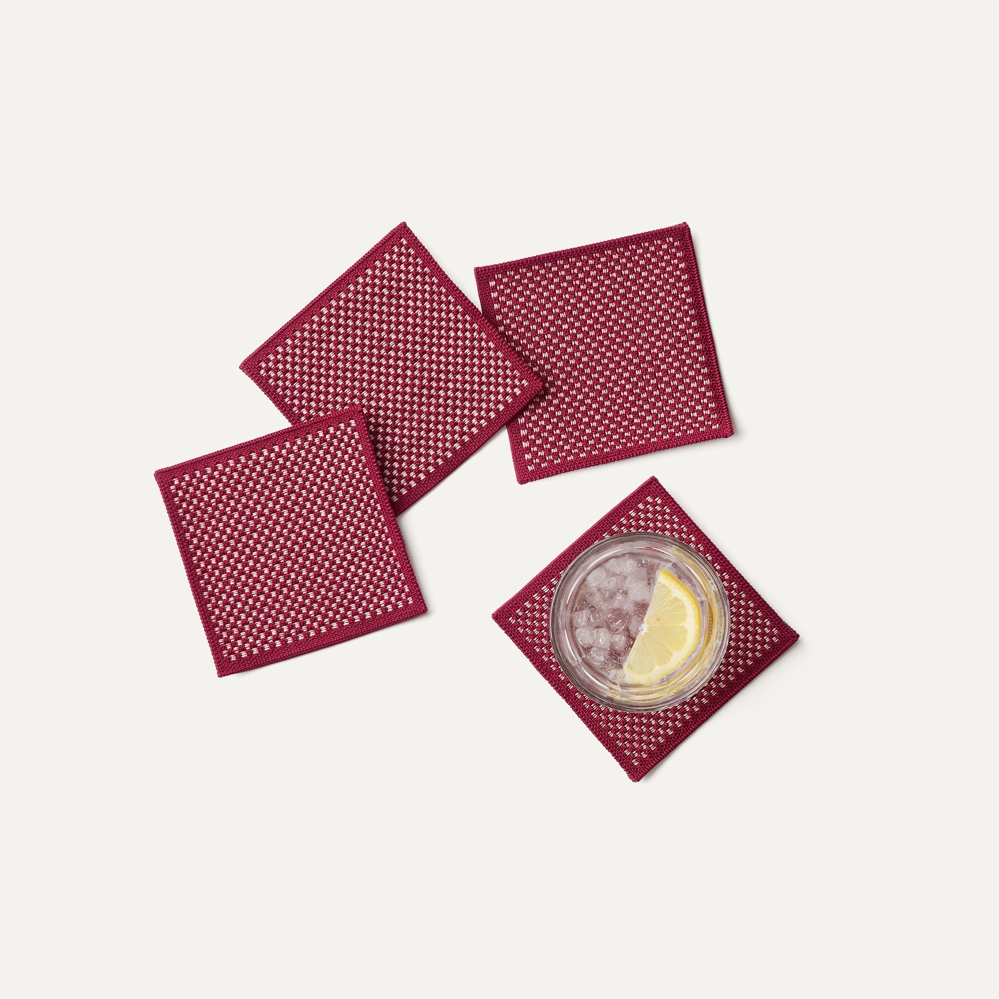 A set of four Coasters in Paprika shown with a drink.