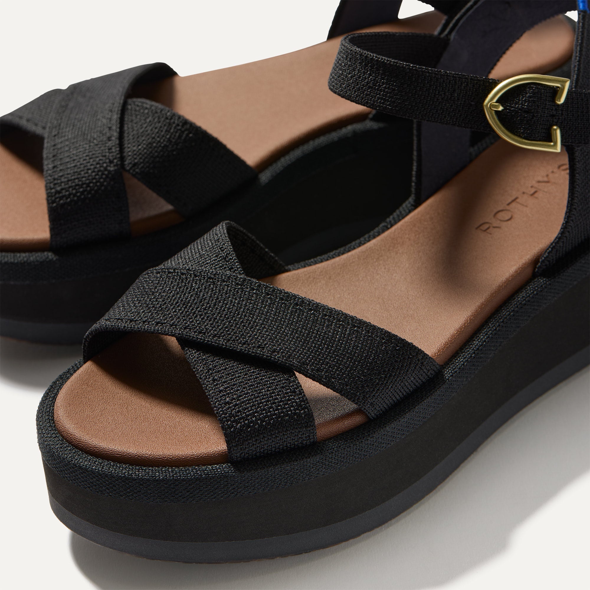 Close up of the straps of The Criss-Cross Lightweight Wedge Sandal in Black, in diagonal view. 