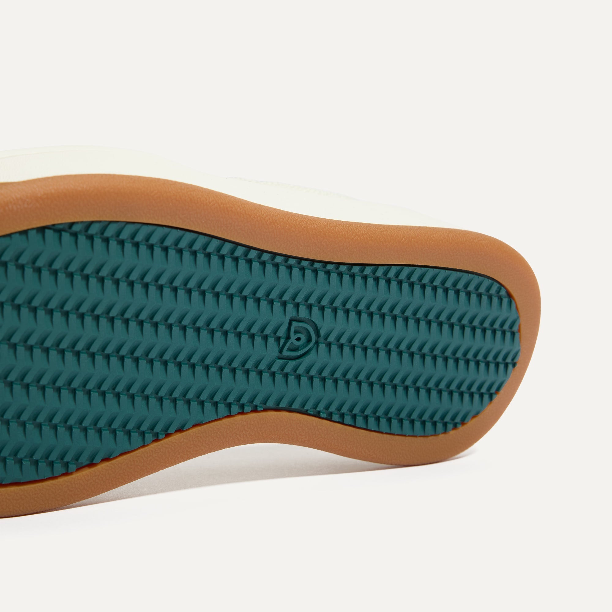 Close up of the outsoles of The Court Sneaker in Birdie, with raised grooves for added traction. 