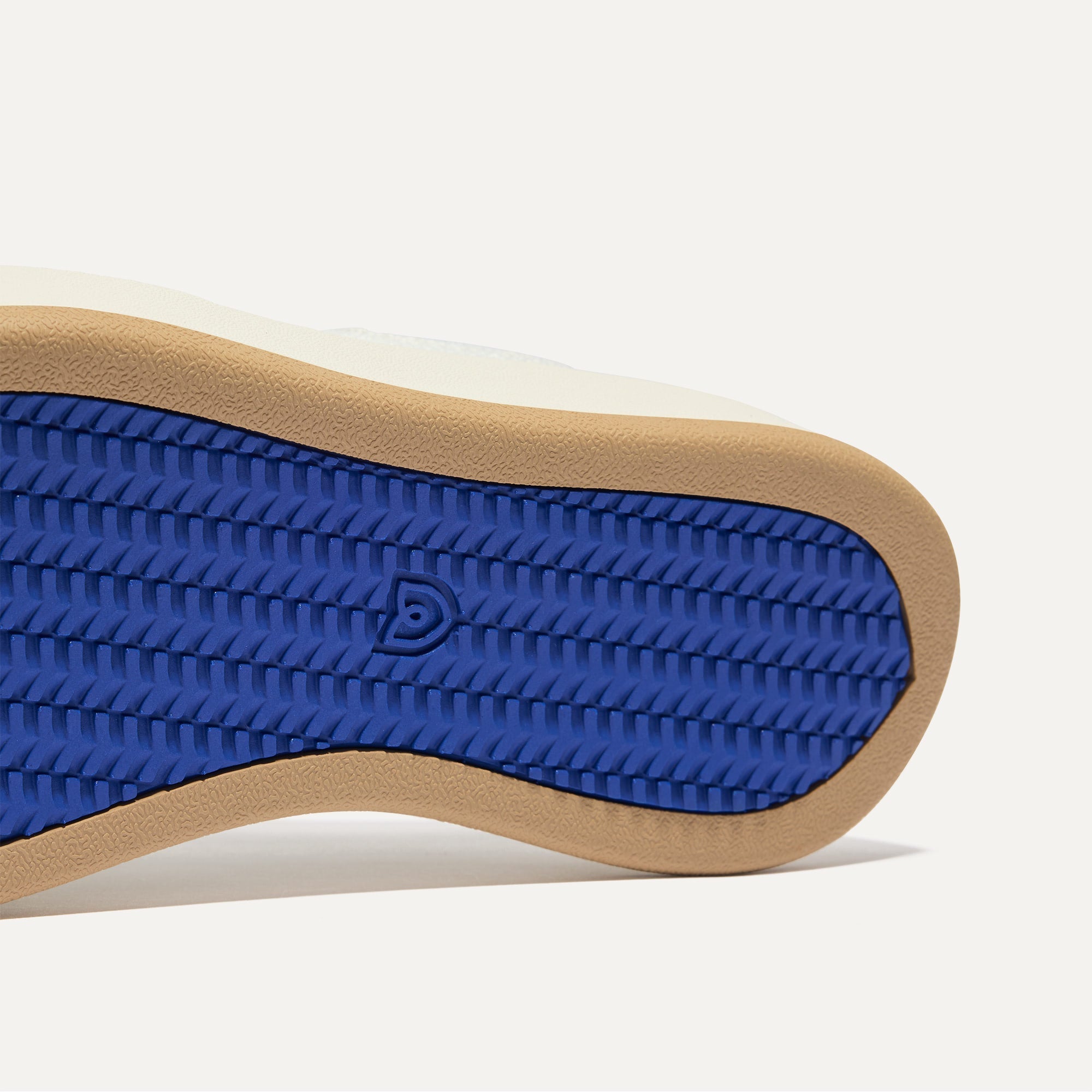 Close up of the outsoles of The Court Sneaker in Bright White, with raised grooves for added traction. 