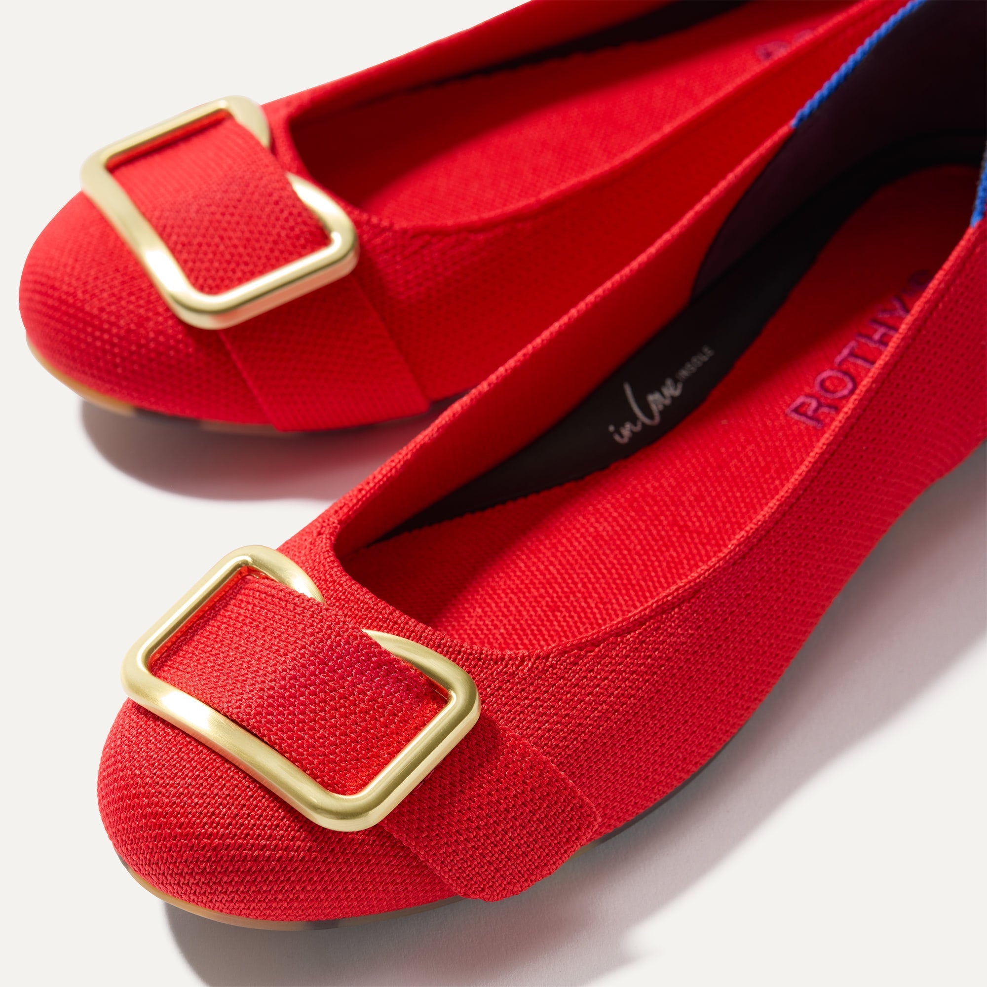 Close up of the gold hardware detail of The Emblem Ballet Flat in Cardinal.