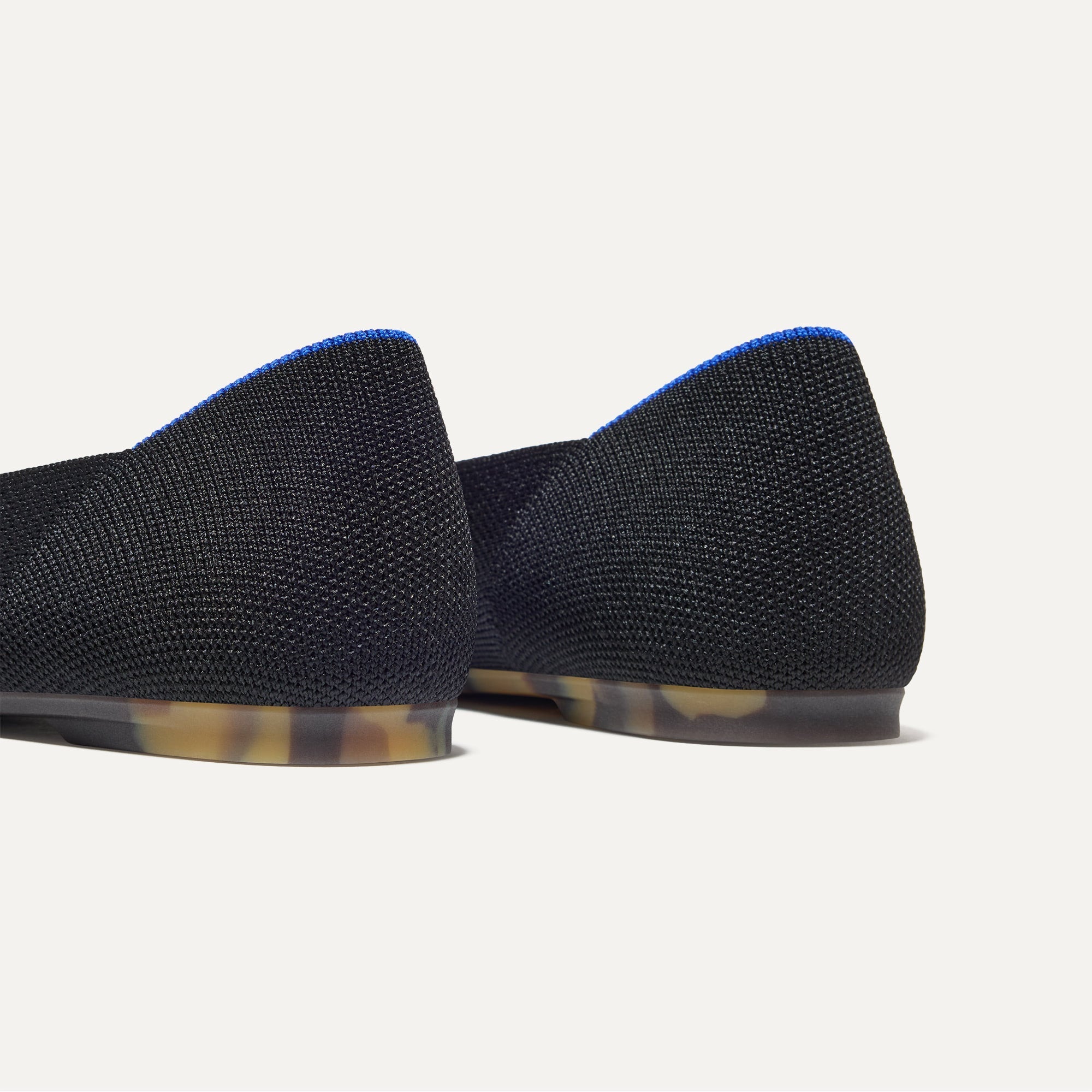Close up of the heel of The Emblem Point II in Black, with Rothy's signature blue halo. 
