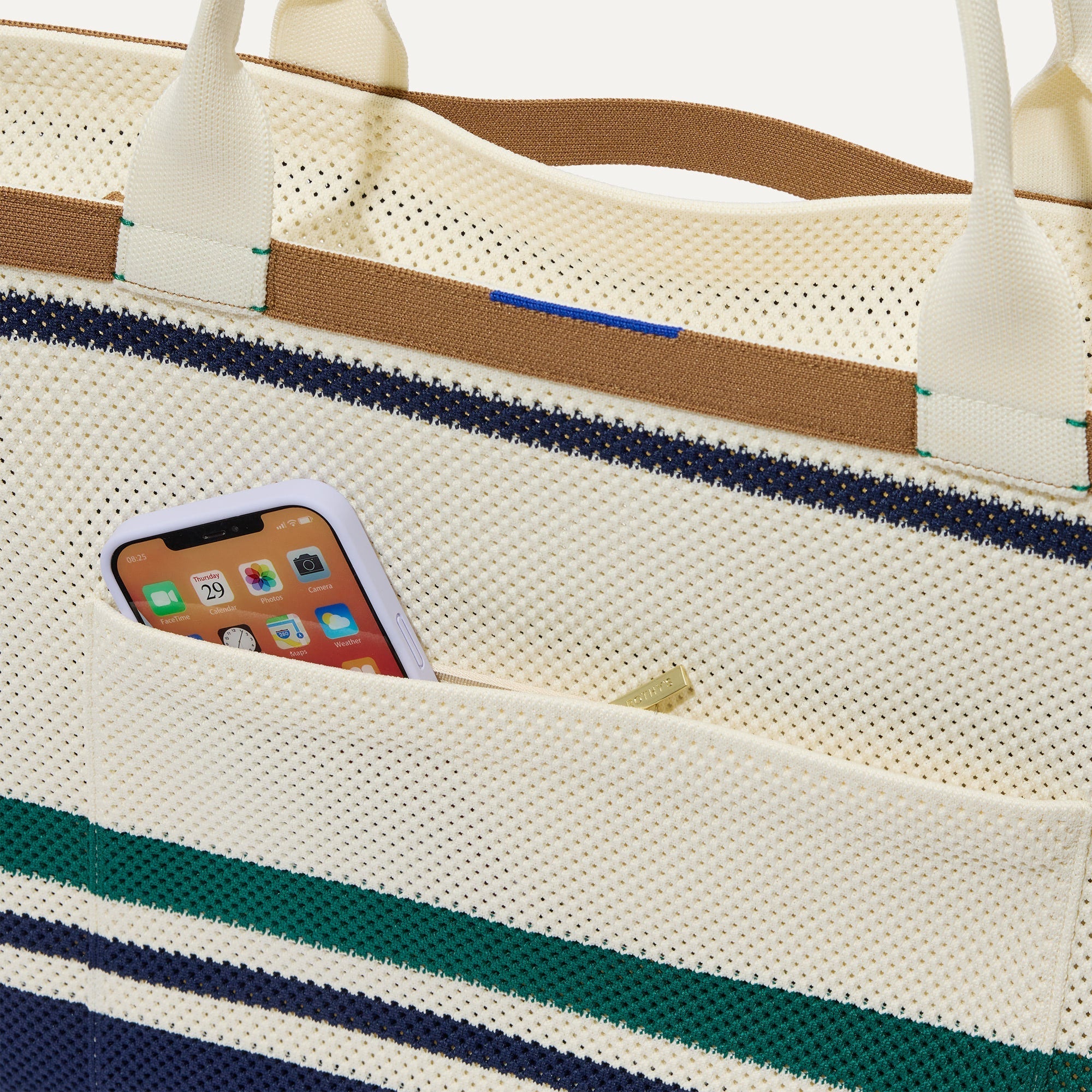 A close up of The Zip Travel Tote in Volley with a phone slipped into the outer pocket.