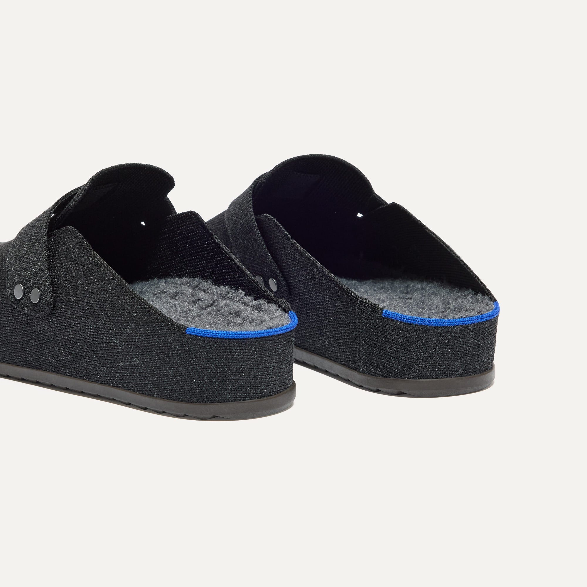 hover | Close up of the heel and sherpa lining of The Men's Cozy Clog in Black, with Rothy's signature blue halo. 
