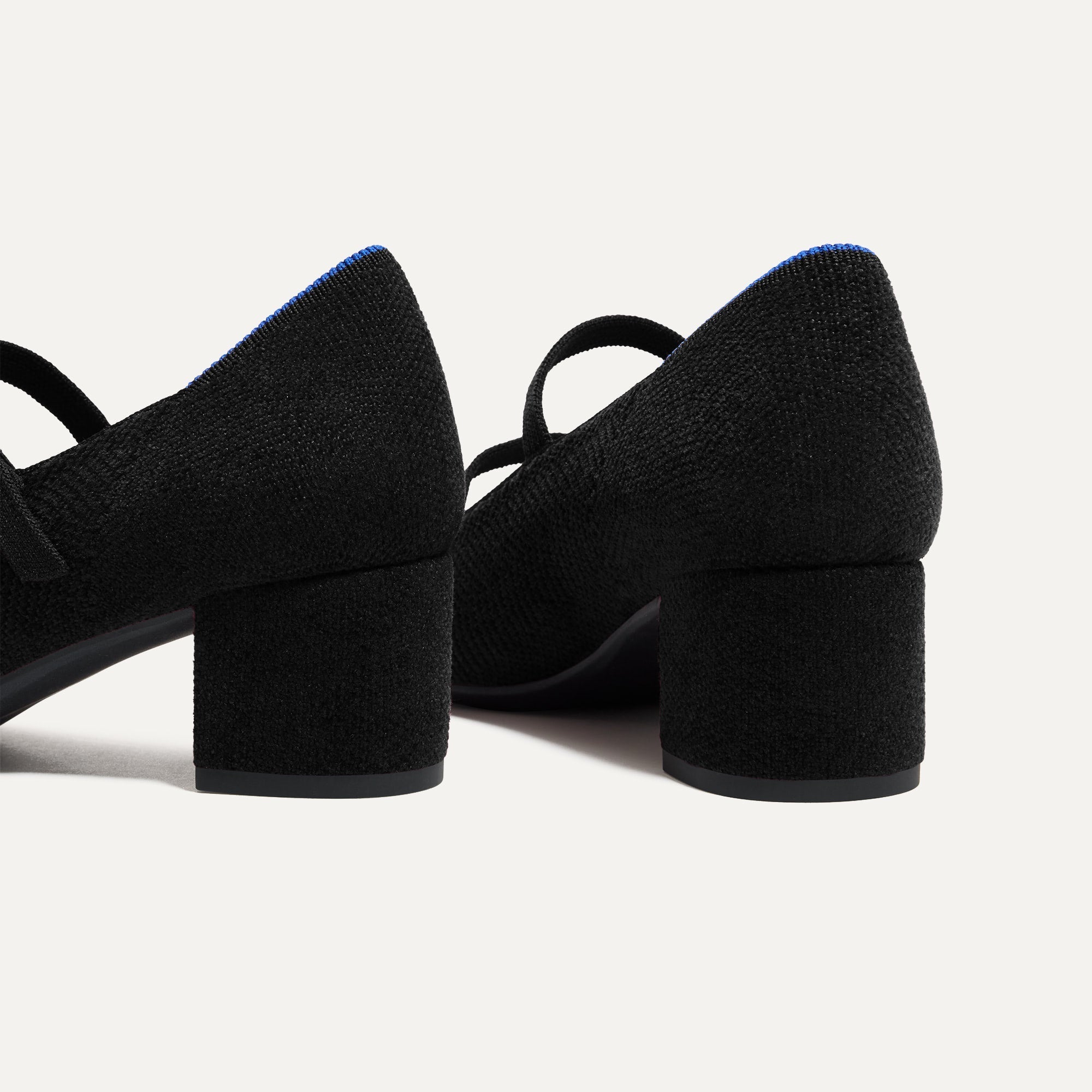 Close up of the heel of The Double Buckle Mary Jane Heel in ReVelvet™ Black, with Rothy's signature blue halo.