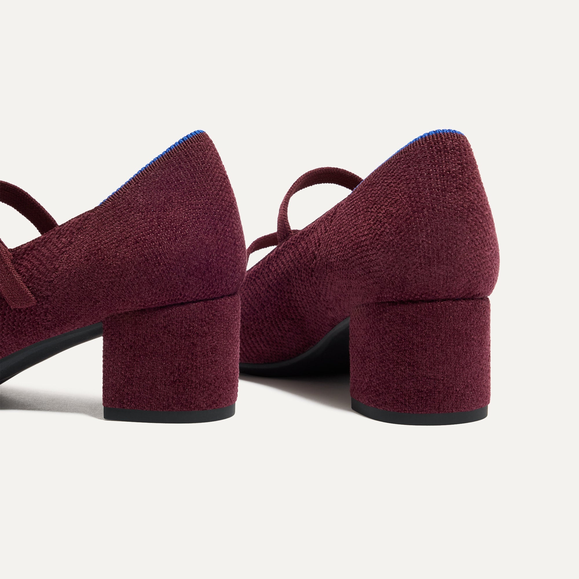 Close up of the heel of The Double Buckle Mary Jane Heel in ReVelvet™ Syrah, with Rothy's signature blue halo.