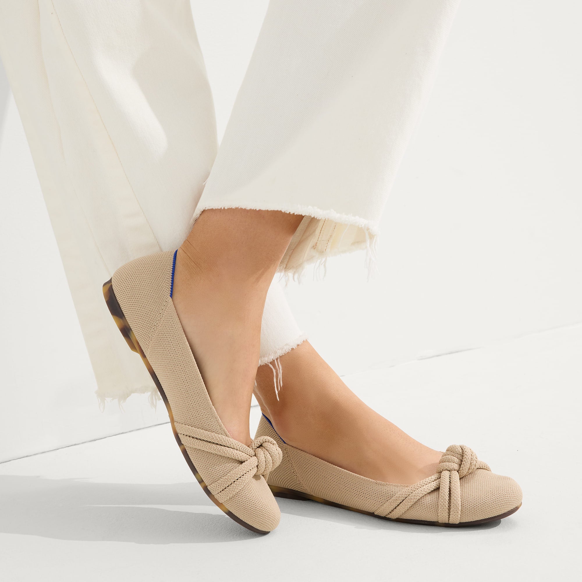 hover | Model wearing The Knot Ballet Flat in Ecru.