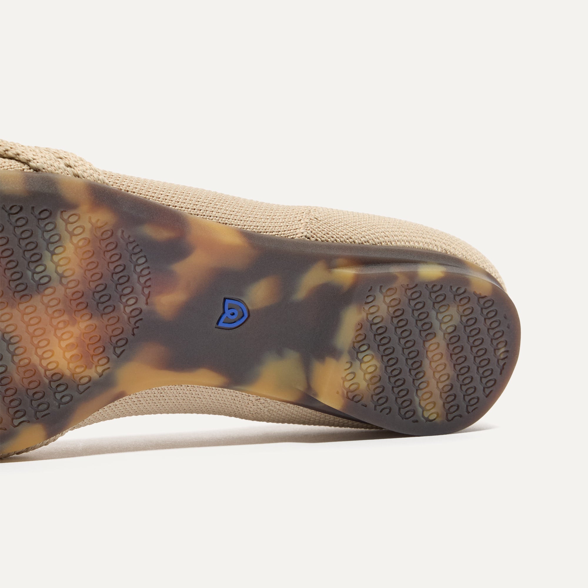 The sole of The Knot Ballet Flat in Ecru shown in diagonal view.