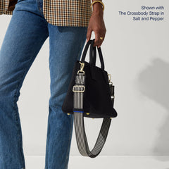 The Classic Handbag in Black being carried by a model shown paired with The Crossbody Strap in Salt and Pepper.