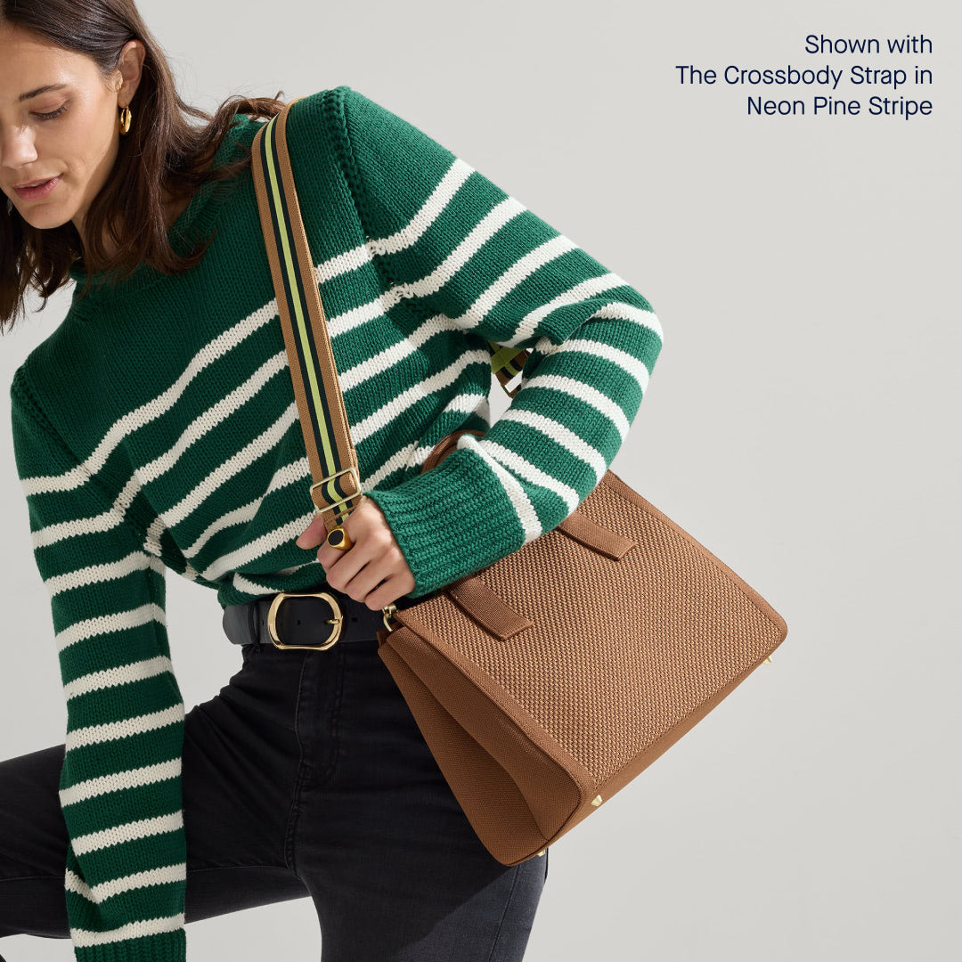 The Classic Handbag in Sierra Brown being carried by a model shown paired with The Crossbody Strap in Neon Pine Stripe.