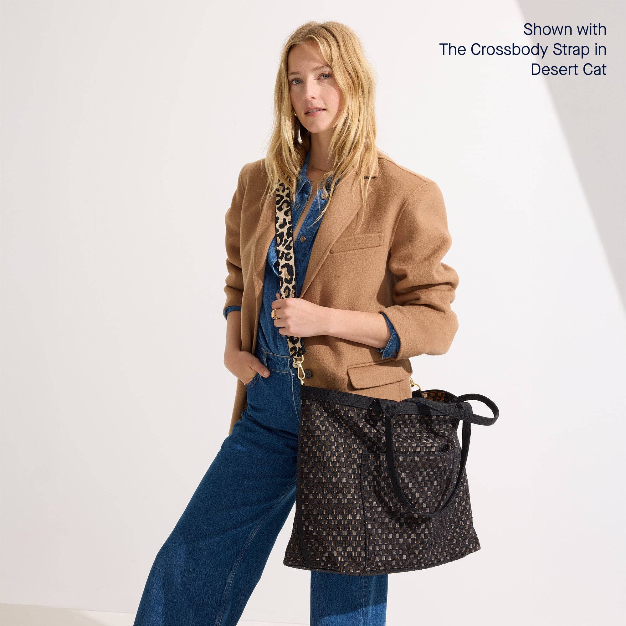 An alternate view of a model holding The Zip Travel Tote in Night Song shown paired with The Crossbody Strap in Desert Cat.